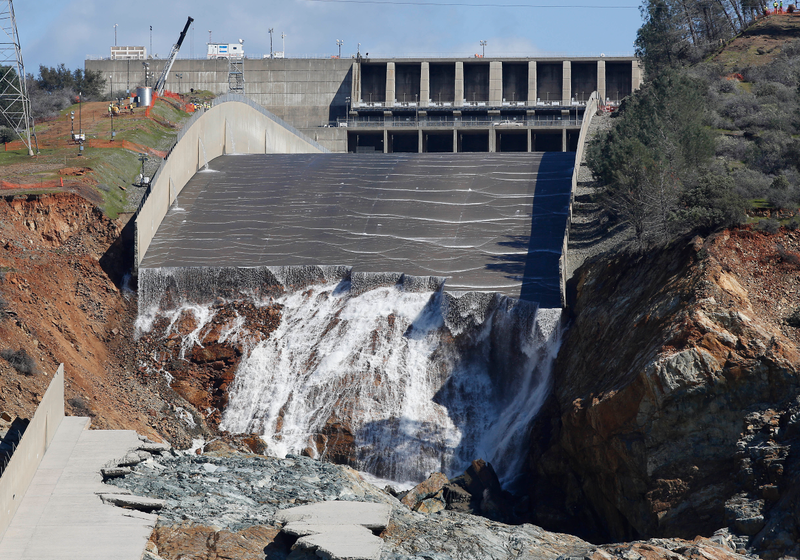 A small flow of water now trickles down the damaged spillway at the Oroville dam as inspectors investigate. Workers at the top left provide a sense of the enormous scale. (Image: AP).